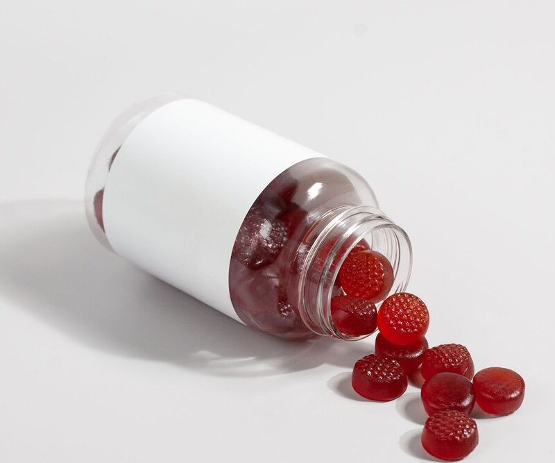 Flacon de gummies rouges renversé, galénique gummy en complément alimentaire