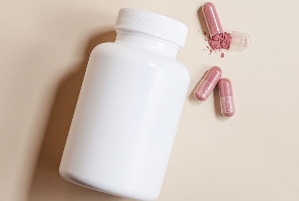 Flacon blanc de complément alimentaire et gélules roses, lancement d'une marque