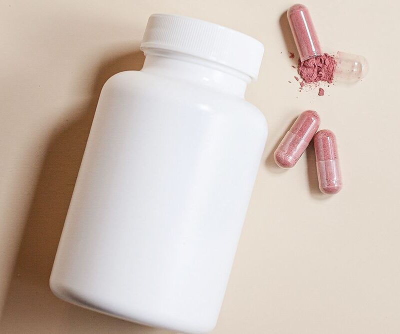 Flacon blanc de complément alimentaire et gélules roses, lancement d'une marque