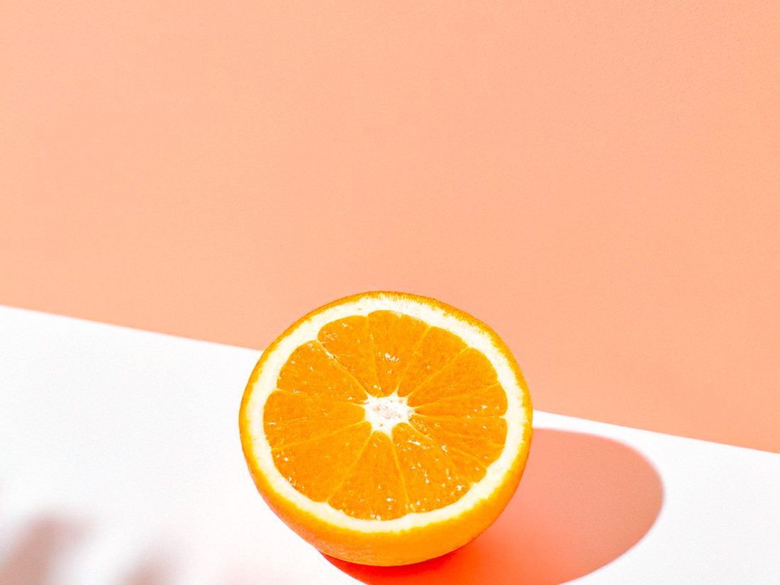 Demi-orange sur fond corail, illustration du travail sur le goût et la formulation sensorielle