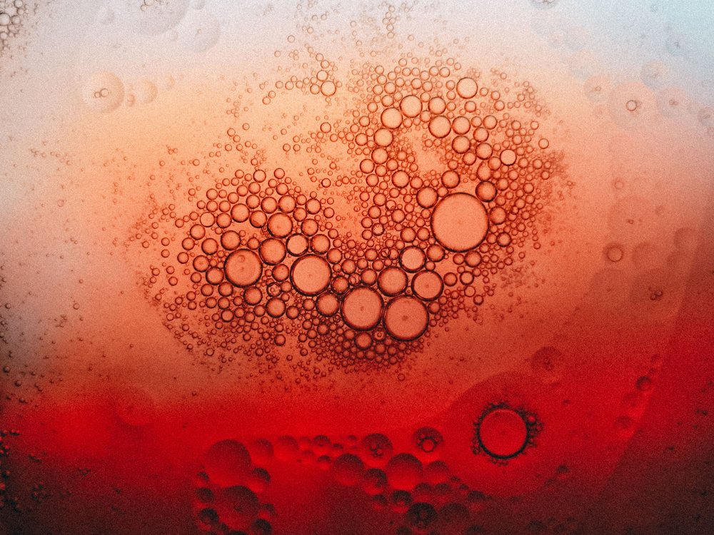 Macrophotographie de bulles dans un liquide rouge, illustration de l'expertise technique en formulation