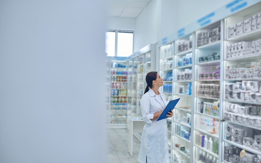 Pharmacienne devant un rayon de compléments alimentaires, illustration de l'observance